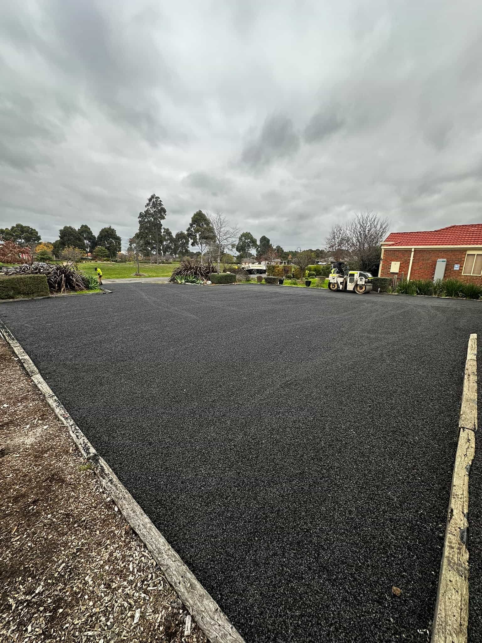 Freshly paved black asphalt driveway in a landscaped residential area