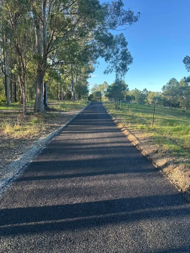 A tree-lined bitumen driveway stretches through a rural acreage property